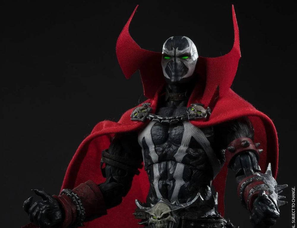 A detailed action figure of Spawn from the DC Comics universe, featuring his signature black and white skeletal armor, a flowing red cape, and a silver helmet with glowing green eyes, posed against a dark studio background.