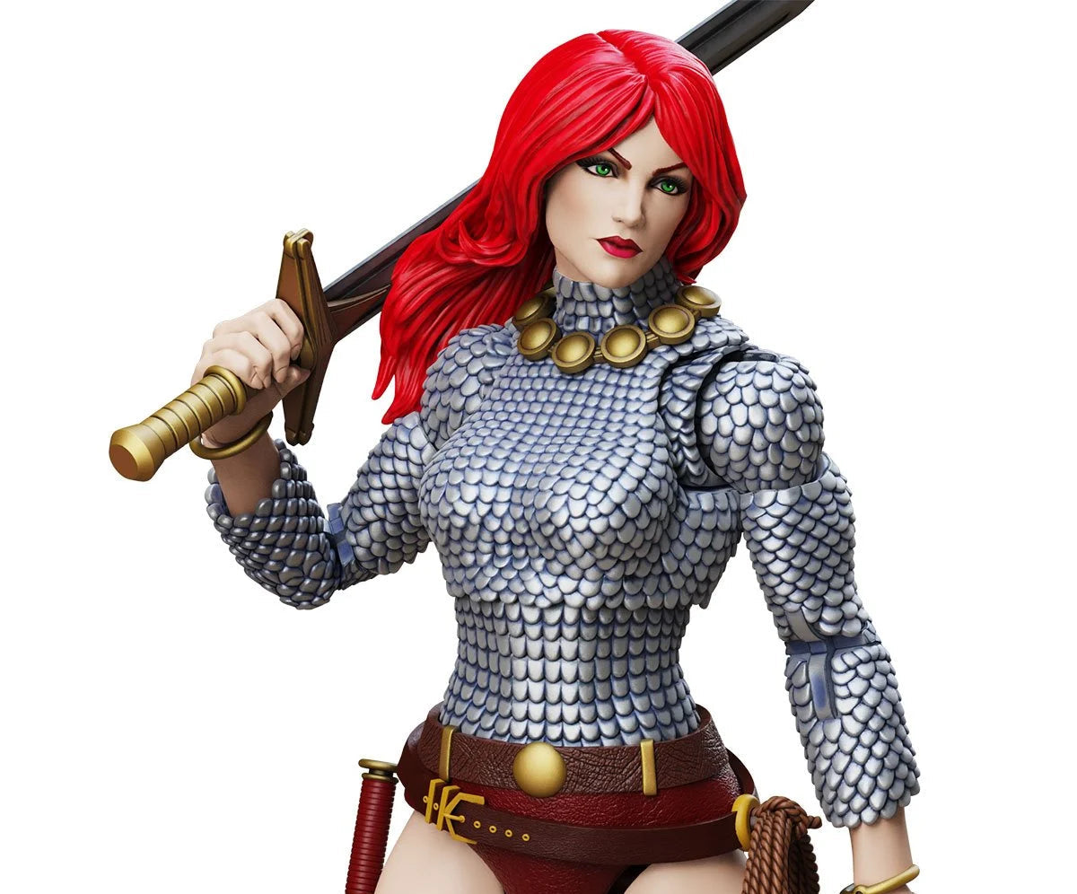 A female warrior action figure or collectible character with long bright red hair, wearing silver chainmail armor, a red belt, brown leather accessories, and holding a sword over her shoulder, shown on a plain white background.